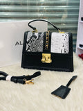 Black handbag with snake print and gold accents on a white surface