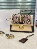 Designer handbag with snake print and gold accents on a white surface