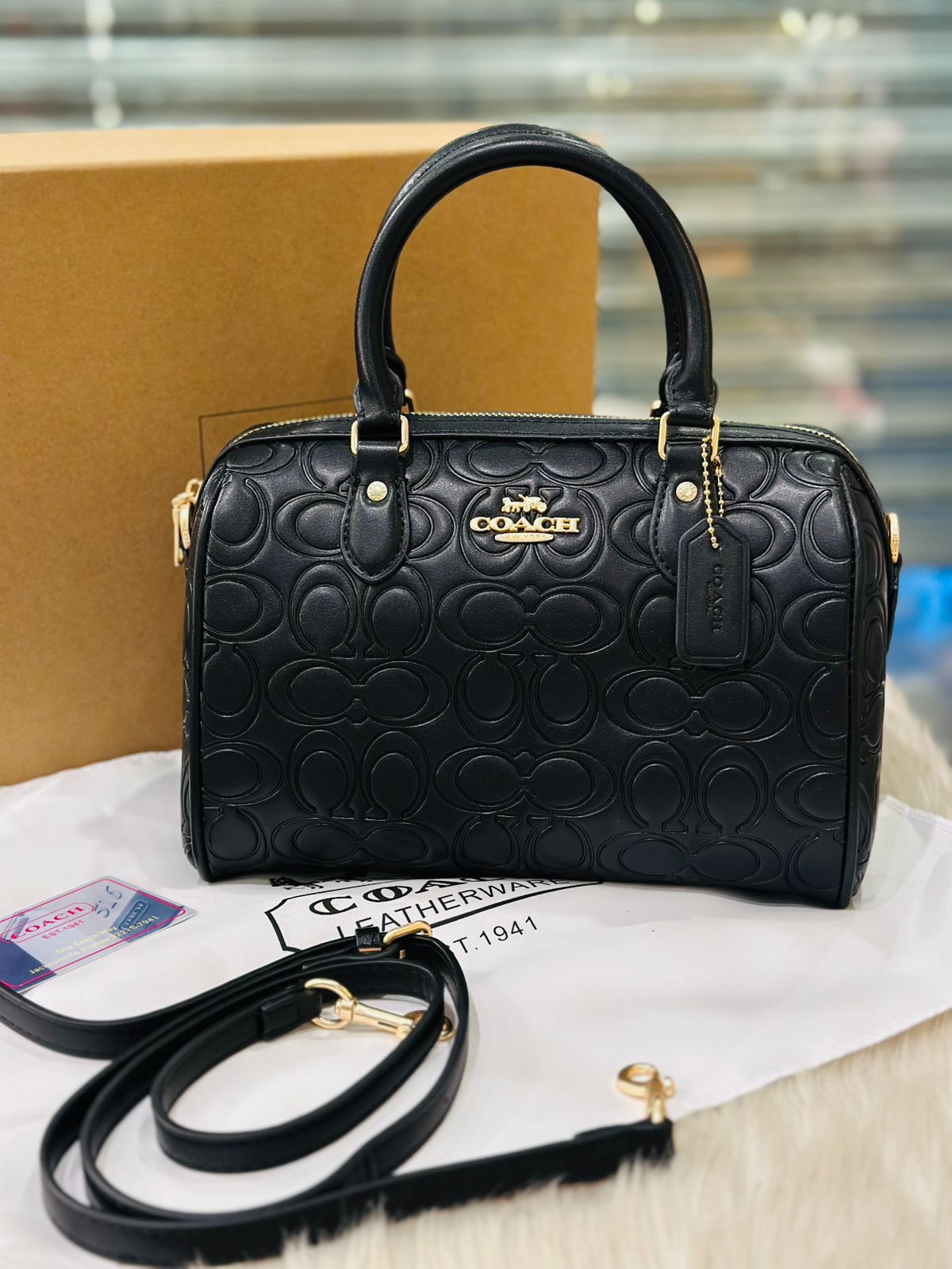 Black Coach handbag with gold accents on a white surface