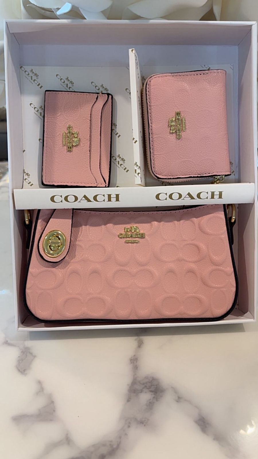 Pink Coach wallet and pouch set in a box on a marble surface