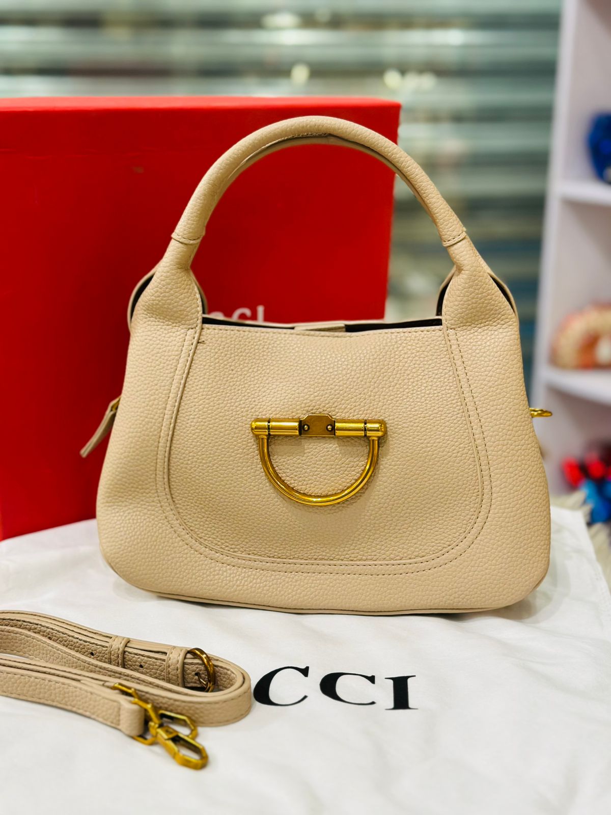 Beige handbag with gold accents on a white surface with Gucci branding.