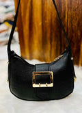 Black handbag with a gold buckle on a blurred background