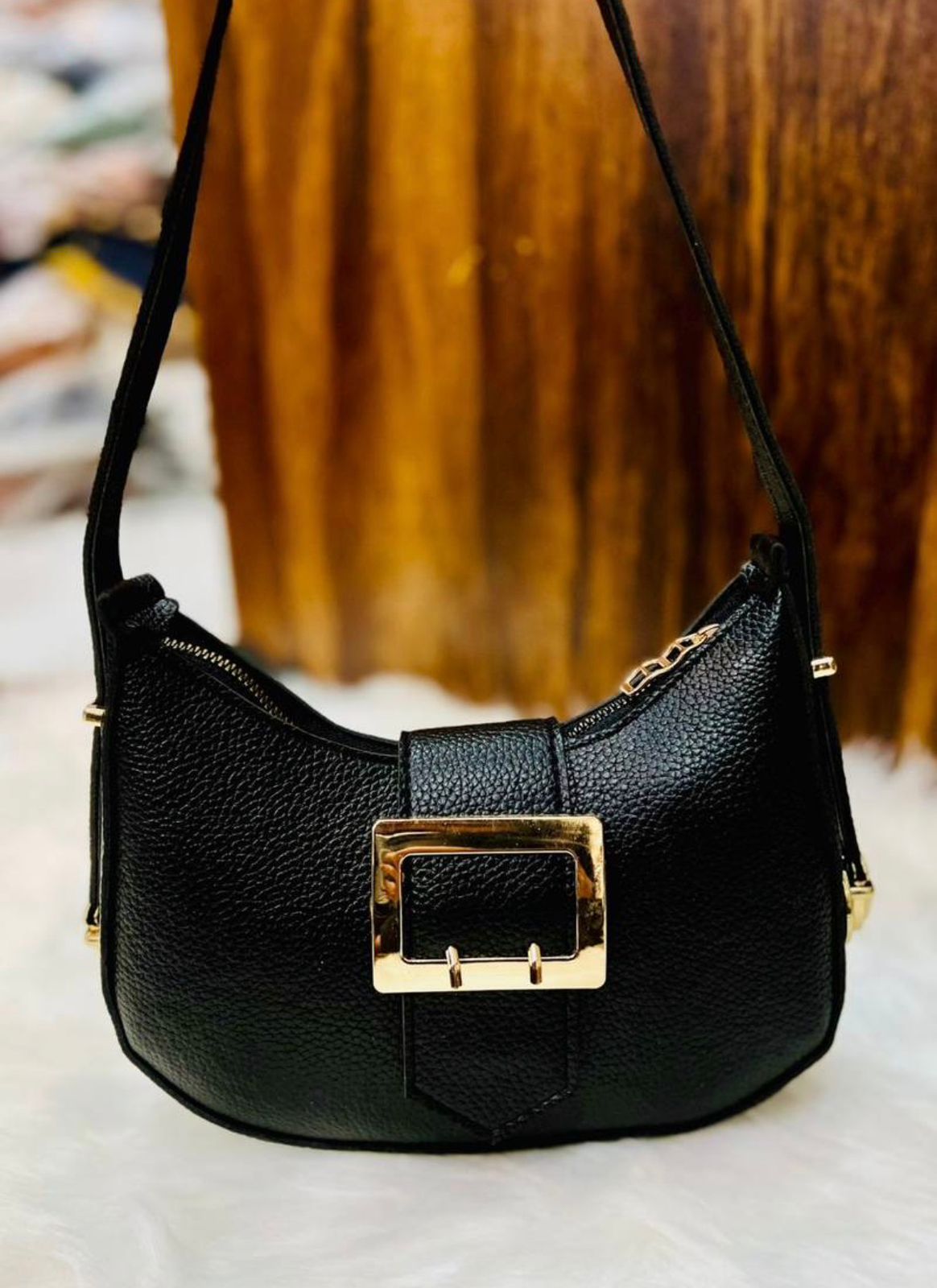 Black handbag with a gold buckle on a blurred background