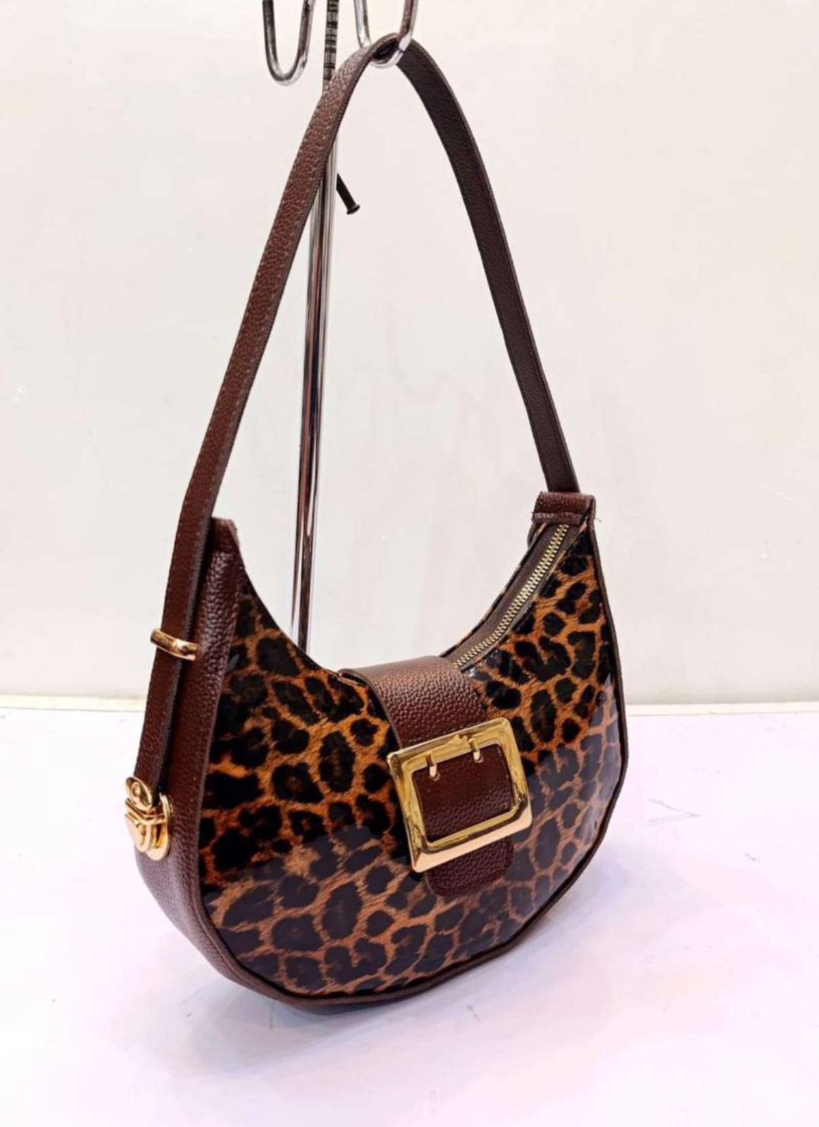 Leopard print handbag with brown leather accents on a white background