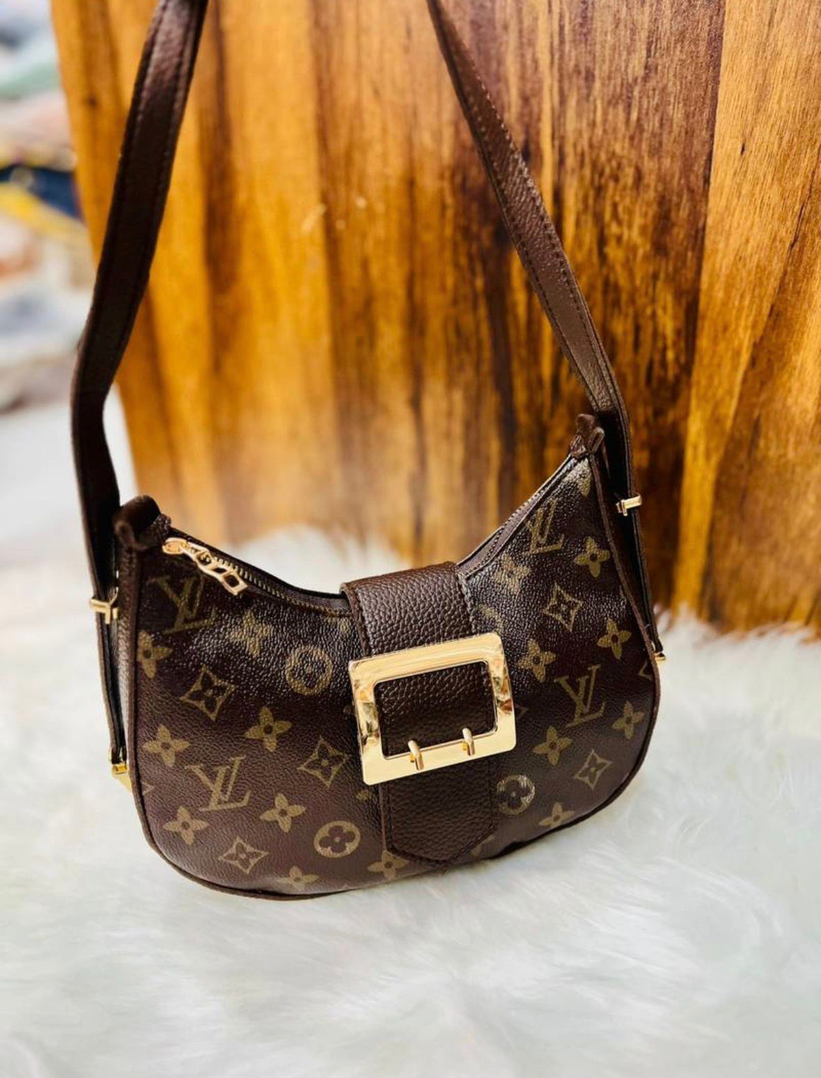 Brown handbag with gold buckle on a textured surface