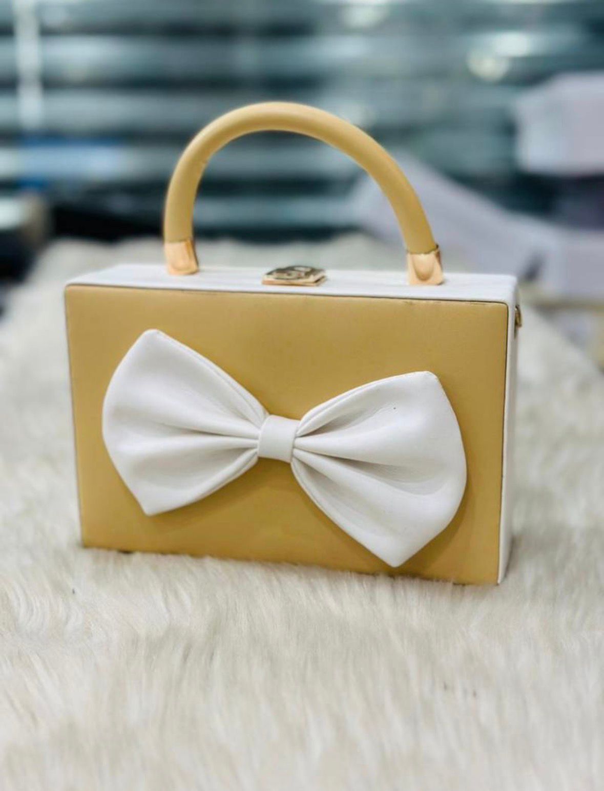 Gold handbag with a large white bow on a light background