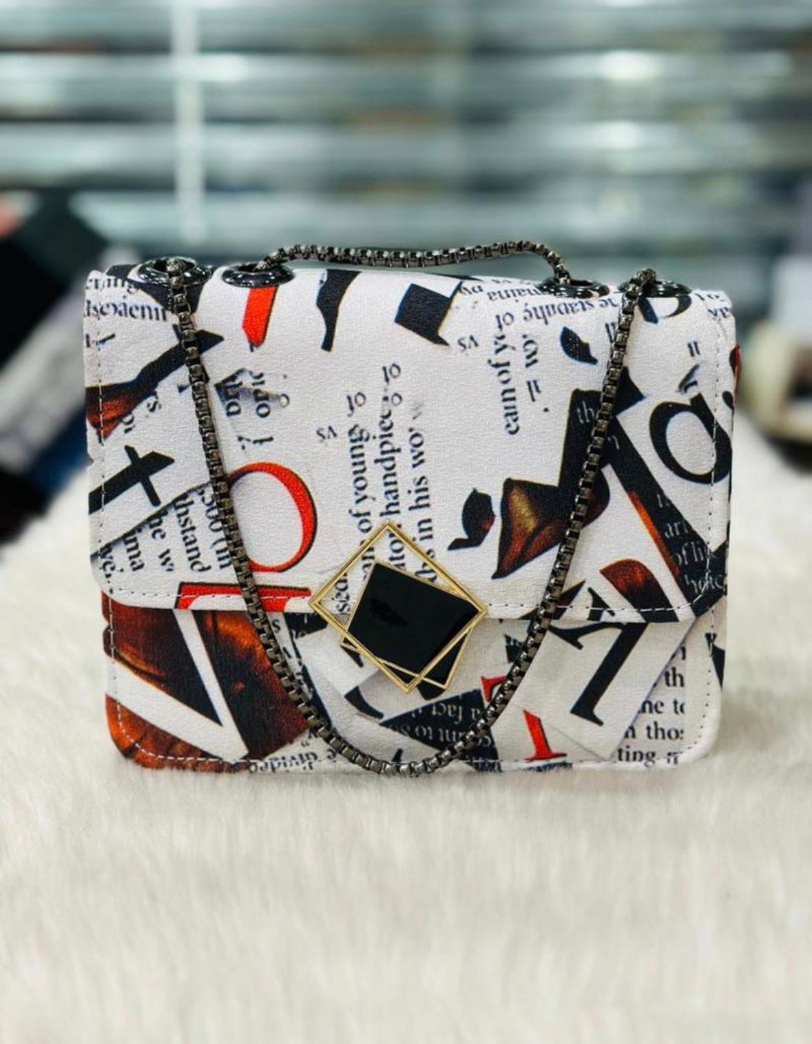 Patterned handbag with chain strap on a textured surface