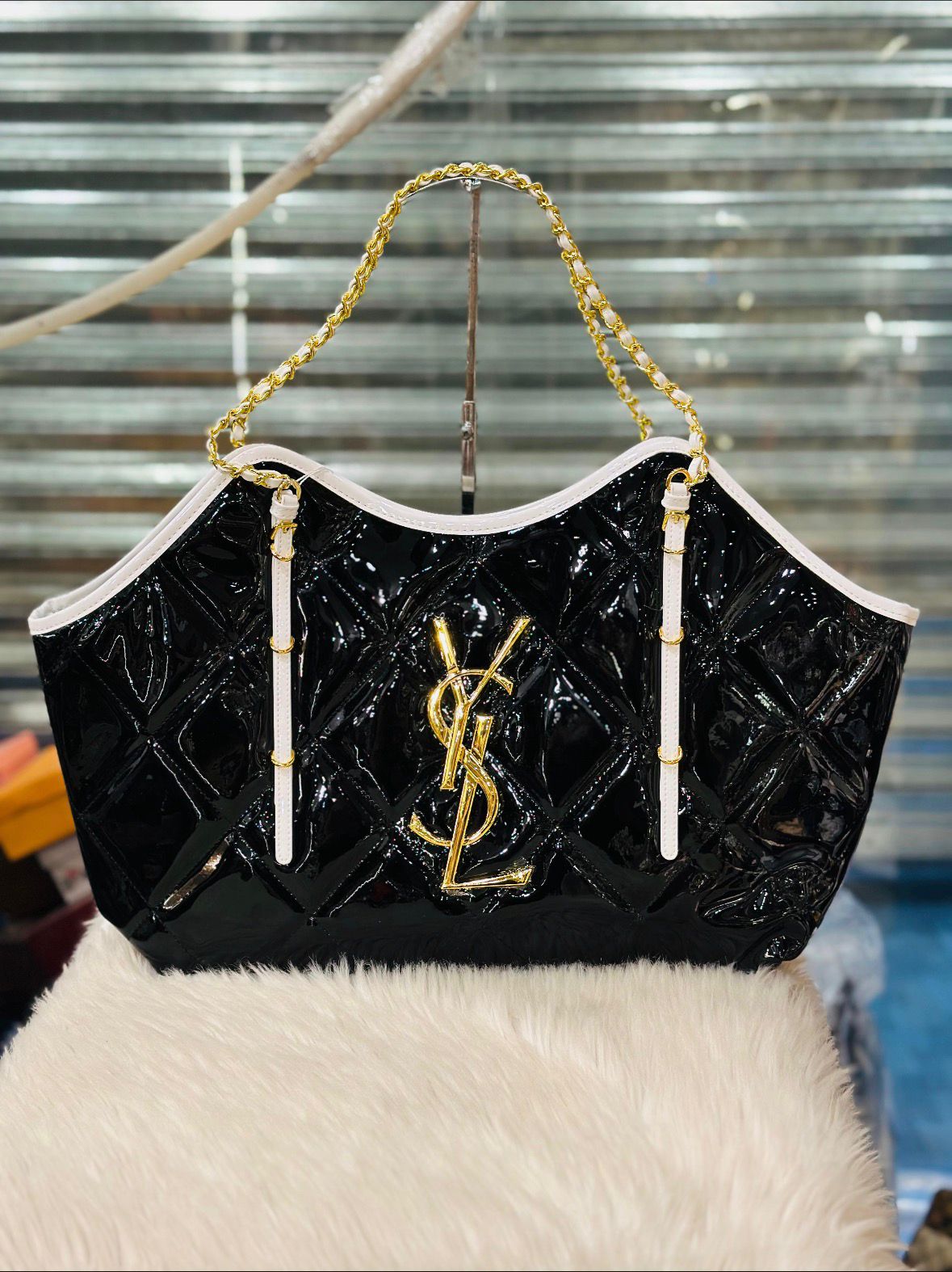 Black handbag with gold chain and logo on a white surface